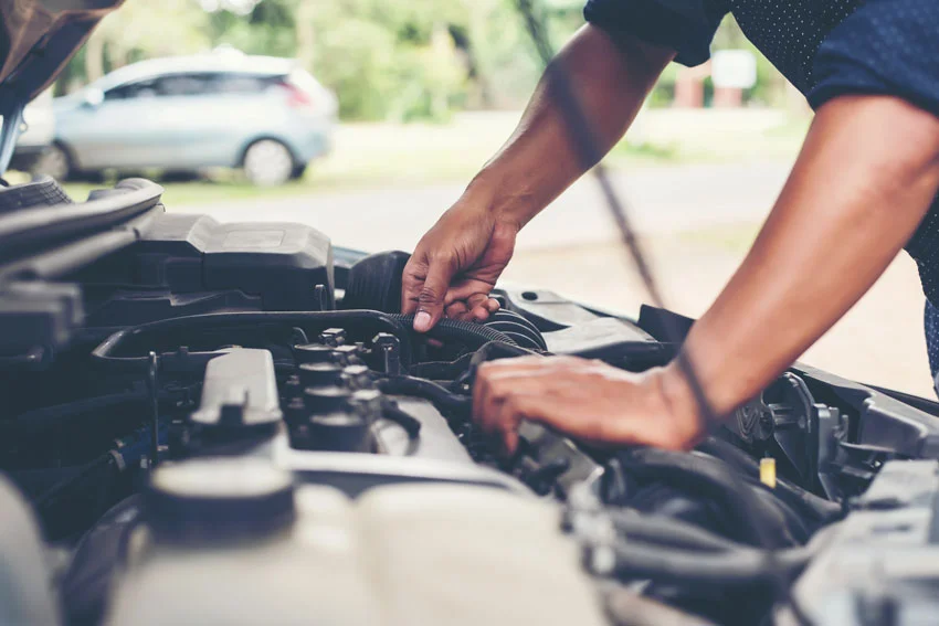 A technician looking underneath the hood of a vehicle
