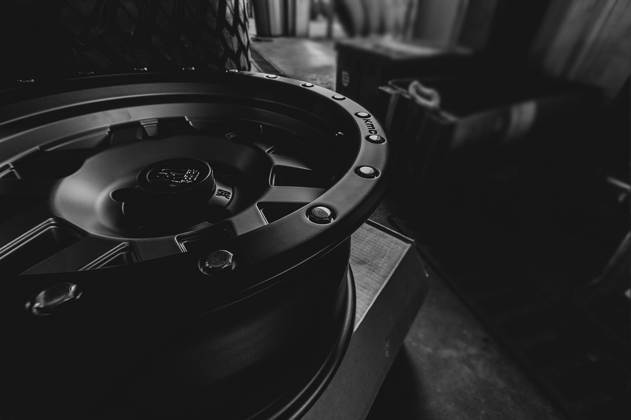 A Jeep wheel with no tire sitting in a dark auto garage