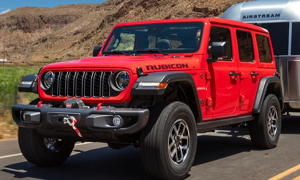 A bright red Jeep Wrangler hauling a trailer