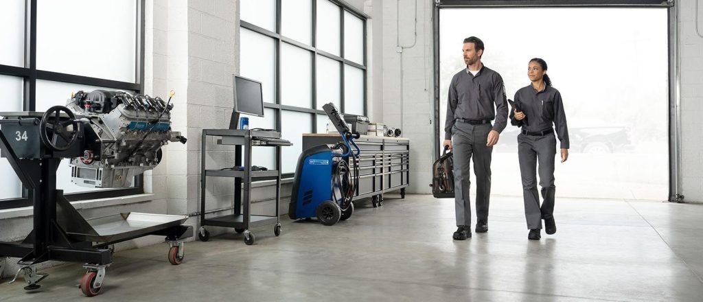 Technicians walking through a bright automotive service bay.